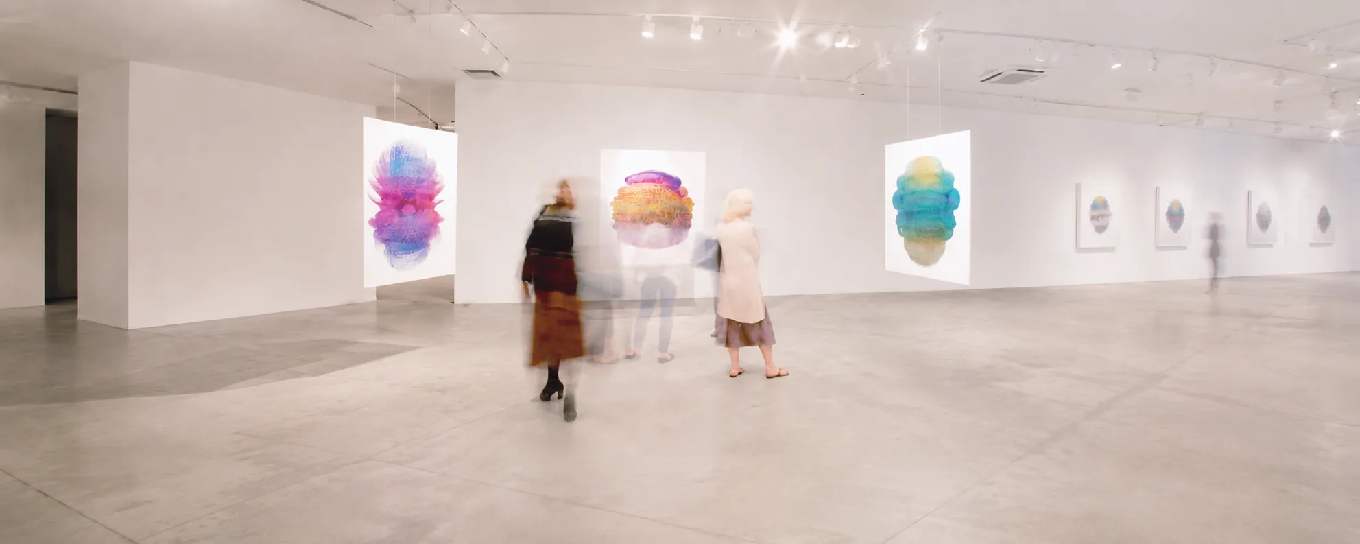 Industry Gallery interior with suspended colorful artworks and blurred visitors